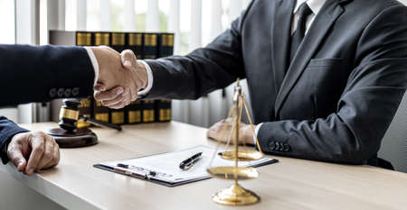 Lawyer and client shake hands, sign a lawsuit for the client, in which the client has filed a lawsuit against an employee of a company that commits fraud. The concept of litigation counseling.の写真素材