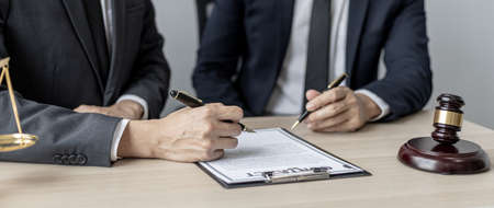 Two male lawyers are consulting together to draft a contract acknowledgment for their clients, they form partnerships to open a law firm. The idea of opening a law firm to accept the lawsuit.の写真素材