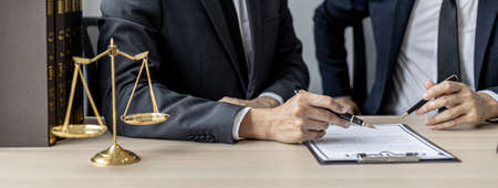Two male lawyers are consulting together to draft a contract acknowledgment for their clients, they form partnerships to open a law firm. The idea of opening a law firm to accept the lawsuit.の写真素材