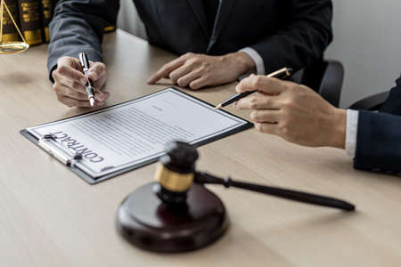Two male lawyers are consulting together to draft a contract acknowledgment for their clients, they form partnerships to open a law firm. The idea of opening a law firm to accept the lawsuit.の写真素材