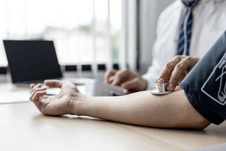 The doctor is checking the blood pressure and listening to the patient's pulse. The concept of annual physical examination for healthy health care and timely disease detection and treatment.の写真素材