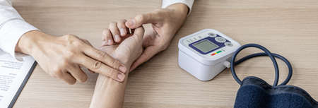 Close-up photo Doctor holding pulse on patient's wrist in the examination room, patient visits...