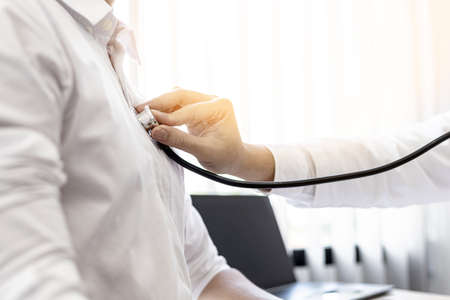 A doctor is using a stethoscope to listen to the lungs of a patient who is being examined in a hospital examination room, the patient has difficulty breathing. The concept of disease examination.の写真素材