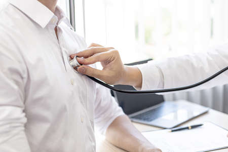 A doctor is using a stethoscope to listen to the lungs of a patient who is being examined in a hospital examination room, the patient has difficulty breathing. The concept of disease examination.の写真素材