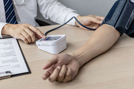 The doctor is checking the blood pressure and listening to the patient's pulse. The concept of annual physical examination for healthy health care and timely disease detection and treatment.の写真素材