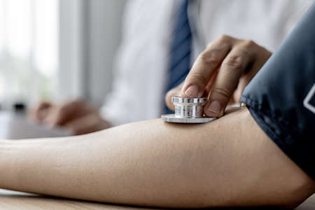 The doctor is checking the blood pressure and listening to the patient's pulse. The concept of annual physical examination for healthy health care and timely disease detection and treatment.の写真素材