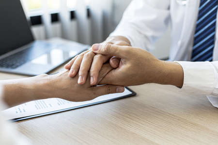 The doctor shakes hands to encourage the patient after the diagnosis results are finished, the...