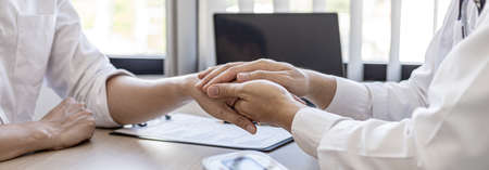 The doctor shakes hands to encourage the patient after the diagnosis results are finished, the...