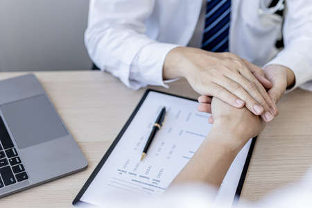 The doctor shakes hands to encourage the patient after the diagnosis results are finished, the...