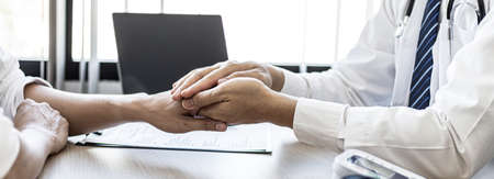 The doctor shakes hands to encourage the patient after the diagnosis results are finished, the patient detected a serious disease in the early stages. Concept of disease diagnosis.の写真素材