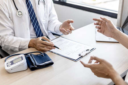 Doctors and patients are talking in the examination room of a private hospital, they are discussing symptoms and treatment of detected diseases. Concept of examination and treatment of disease.の写真素材