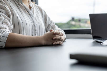 A woman holding her hand on a table, a female worker approaches the manager to discuss the task assigned to the manager explaining the job details and problems encountered. Professional work concept.の写真素材