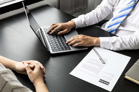 The atmosphere of the job interview room has HR and job applicants checking resumes, HR is typing applicants' information into laptops to send information to the system to the department manager.の写真素材