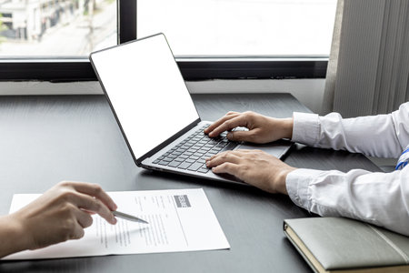 The atmosphere of the job interview room has HR and job applicants checking resumes, HR is typing applicants' information into laptops to send information to the system to the department manager.の写真素材
