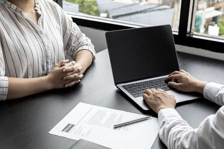 The atmosphere of the job interview room has HR and job applicants checking resumes, HR is typing applicants' information into laptops to send information to the system to the department manager.の写真素材