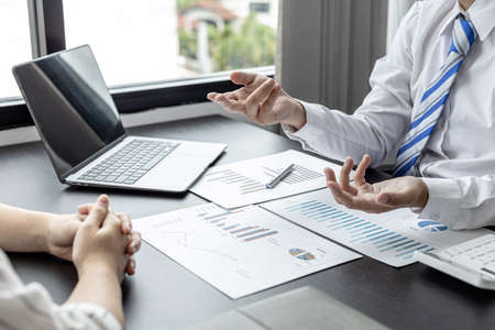 A businessman is explaining to his business partners in detail how to solve a sales fall problem so that they can make joint decisions to manage their sales growth. Company management concept.の写真素材