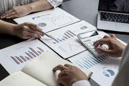 Two businessmen are reviewing the earnings summary and company financial documents that each department produces and submits for monthly audits. Concept of checking company information sheet.