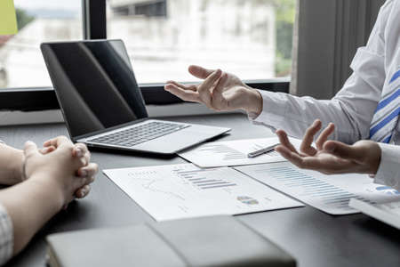 A businessman is explaining to his business partners in detail how to solve a sales fall problem so that they can make joint decisions to manage their sales growth. Company management concept.の写真素材