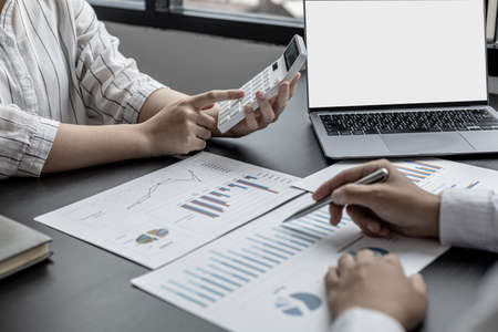 A businesswoman pressing a white calculator, she is a senior executive of the company, she is meeting with a sales manager to brainstorm solutions and plans to grow sales. Sales management concept.の写真素材