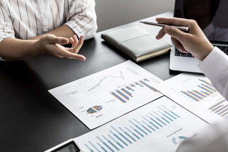 A businessman holding a pen and pointing to a businesswoman, he is explaining the problem of falling sales to business partners in detail to make a decision. Company management concept.の写真素材