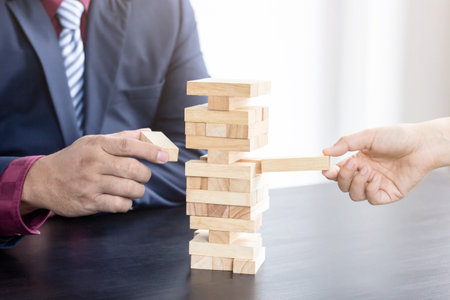 Businessmen and businesswomen are playing wood blocks together at the break, leisure activities to...