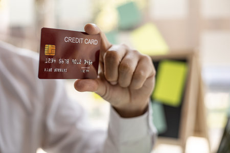 A man with a red credit card and a smartphone is filling out his credit card information in order to pay for online purchases ordered from online shopping sites. Concept of using a credit card.の写真素材