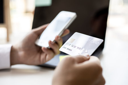 A man with a Silver credit card and a smartphone is filling out his credit card information in order to pay for online purchases ordered from online shopping sites. Concept of using a credit card.の写真素材