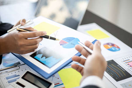 Two partner businessmen are meeting together with various information and charts about the company's finances as a meeting sheet, they form a joint startup company and manage the company to grow more.の写真素材