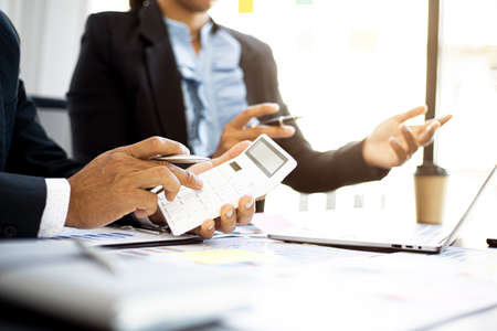Executives are examining numbers from the company's financial documents with white calculators, a...