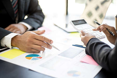 Executives are examining numbers from the company's financial documents with white calculators, a meeting between the executives and the company's finance team meets. Financial concept.の写真素材