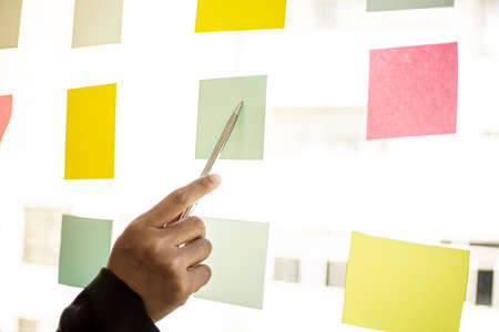 Business men are writing on a note that is placed in the glass of the conference room to brainstorm...