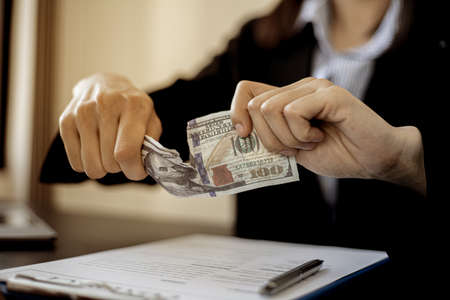 Businessmen are ripping off the dollar bills, the money their business partners bring to bribe, businesswomen refusing to accept bribes from business partners offering money to corrupt companies.の写真素材