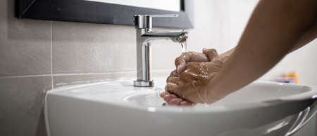People washing their hands in the sink, washing their hands thoroughly is a precautionary measure against   infection. Everyone washes their hands regularly in the right way.の写真素材