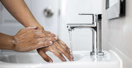 People washing their hands in the sink, washing their hands thoroughly is a precautionary measure against  infection. Everyone washes their hands regularly in the right way.の写真素材