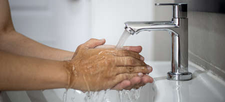 People washing their hands in the sink, washing their hands thoroughly is a precautionary measure against  infection. Everyone washes their hands regularly in the right way.の写真素材