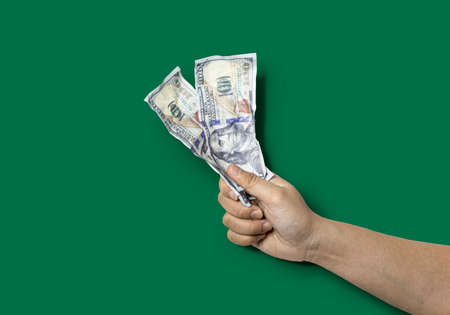 Close-up of a hand holding two wrinkled dollar bills. Crumpled dollar bills cause signs of wrinkling. Isolated on green backgroundの写真素材