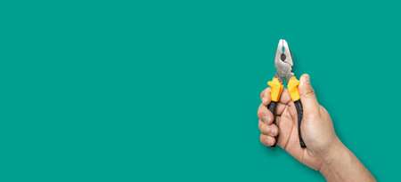 Person holding yellow handle pliers, hand tools, Isolated on green backgroundの写真素材