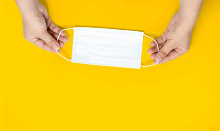 The person is holding the mask strap with two hands, Put on a mask to protect against virus,...