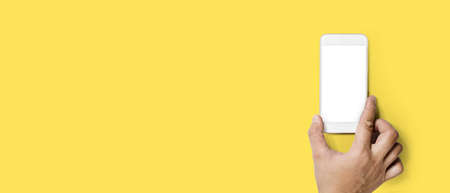 Person holding cell phone with his right hand, Isolated on yellow backgroundの写真素材