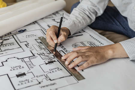 Architect uses a ruler to measure the blueprints of the houses he designed, designing the buildings...