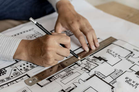 Architect uses a ruler to measure the blueprints of the houses he designed, designing the buildings according to the standards and the law, designing the houses according to the needs of the residentsの写真素材