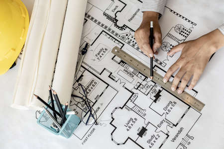 Architect uses a ruler to measure the blueprints of the houses he designed, designing the buildings according to the standards and the law, designing the houses according to the needs of the residentsの写真素材