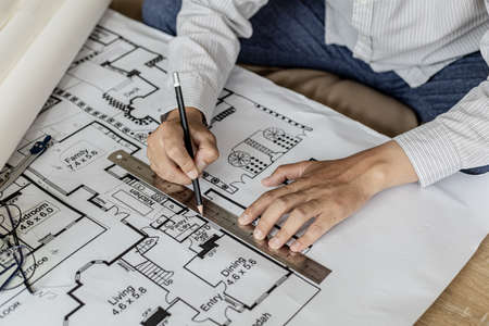 Architect uses a ruler to measure the blueprints of the houses he designed, designing the buildings according to the standards and the law, designing the houses according to the needs of the residentsの写真素材