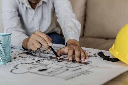 Architect uses a ruler to measure the blueprints of the houses he designed, designing the buildings according to the standards and the law, designing the houses according to the needs of the residentsの写真素材