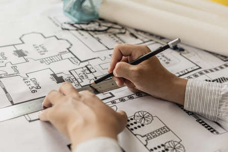 Architect uses a ruler to measure the blueprints of the houses he designed, designing the buildings...