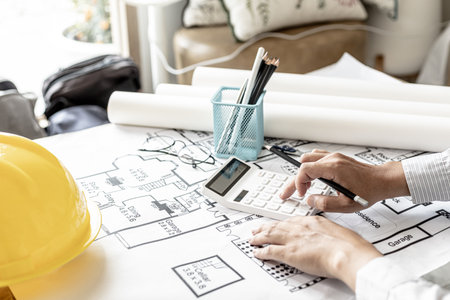 The architects pressed a calculator to calculate the area in a blueprint, designing the house according to the homeowner's requirements and according to the construction standards. Home design ideas.の写真素材