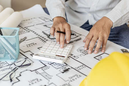 The architects pressed a calculator to calculate the area in a blueprint, designing the house...