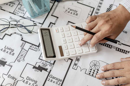 The architects pressed a calculator to calculate the area in a blueprint, designing the house according to the homeowner's requirements and according to the construction standards. Home design ideas.の写真素材