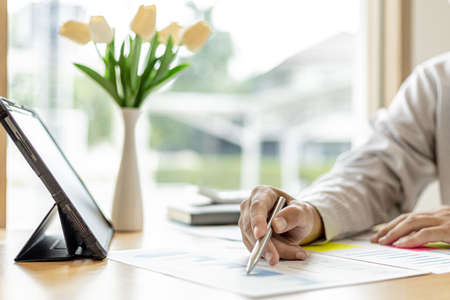 The financial officer uses a pen to point at the numbers on the financial documents to verify the correctness before submitting the information in the documents to the meeting. Finance concept.の写真素材