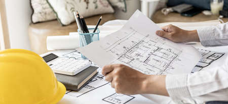 Architects review the blueprints for accuracy, designing the house according to the homeowner's...